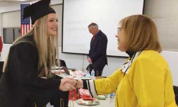 Ava Bockbrader receives a congratulatory handshake from school board member Sue Larimer.